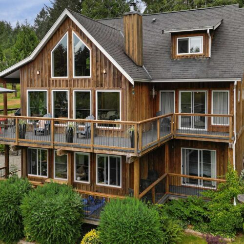 Large cabin with peaked roof, large deck and lots of windows located in Sooke BC