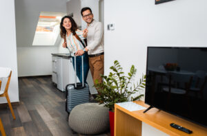 smiling couple with a suitcase enter a room - vacation rentals