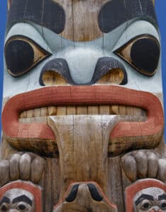 close up of a first nations totem pole - blue, red and black paint on the wood carving