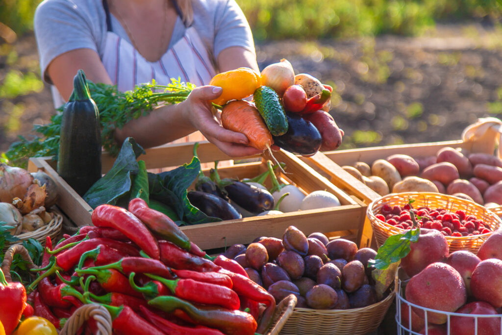 woman selling fresh produce at a farm market pesspers, potatoes, tomatoes etc.