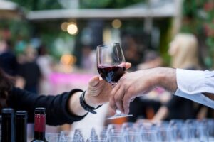 someone wearing a dark shirt taking a glass of wine from someone - wine event