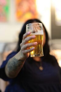 woman with a tattoo on her arm holding up a beer
