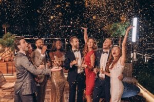 Group of happy people in formalwear having fun together with confetti flying all around