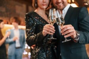 Couple is posing. Group of people in beautiful elegant clothes are celebrating New Year indoors together