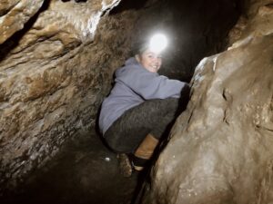 young girl exploring a cave with a headlamp on