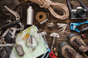 Equipment necessary for mountaineering and hiking on wooden background