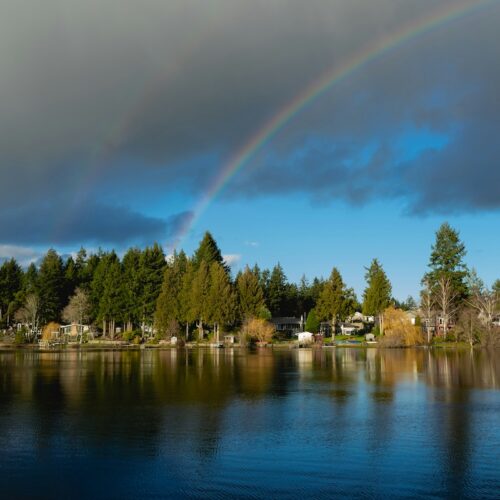 downtown Victoria neighbourhood seen from the water with a rainbow above