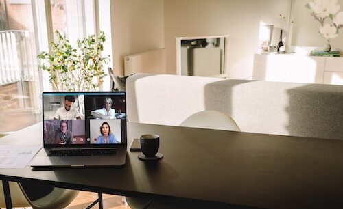 Laptop on table with a video call on the screen in living room. People using VoIP to connect together.