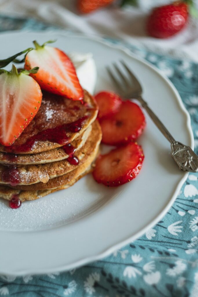 pancakes on a white plate with strawberries on top