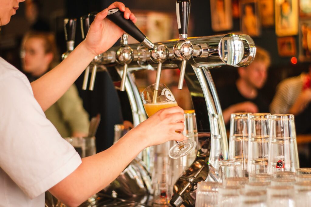person pouring a beer from a tap - brewery
