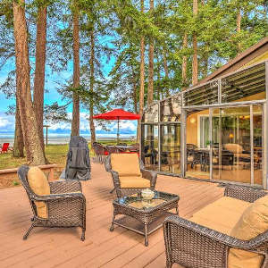 outdoor patio at Kye Bay beach house with comfortable outdoor furniture and the ocean and private beach access in the distance